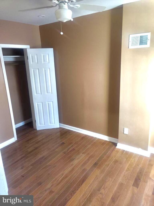 unfurnished bedroom featuring wood finished floors, baseboards, a closet, and ceiling fan