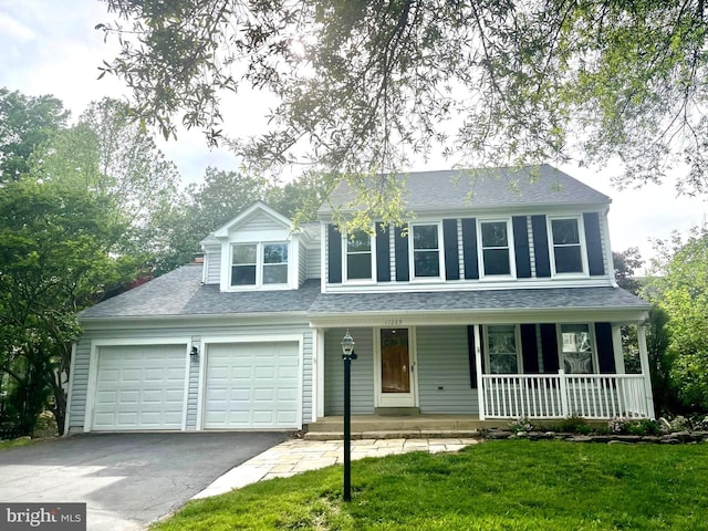 view of front facade featuring asphalt driveway, covered porch, roof with shingles, a garage, and a front lawn