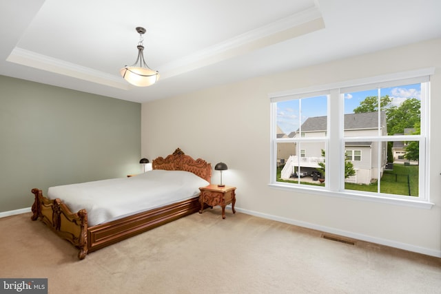 carpeted bedroom featuring a tray ceiling, crown molding, and baseboards