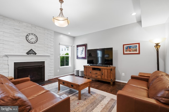 living area featuring wood finished floors, baseboards, and a stone fireplace