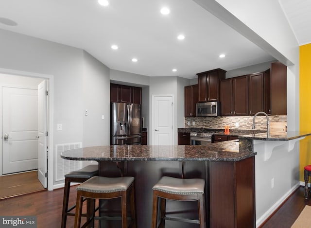 kitchen with appliances with stainless steel finishes, baseboards, dark wood-style floors, recessed lighting, and a peninsula