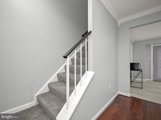 staircase with crown molding, wood finished floors, and baseboards
