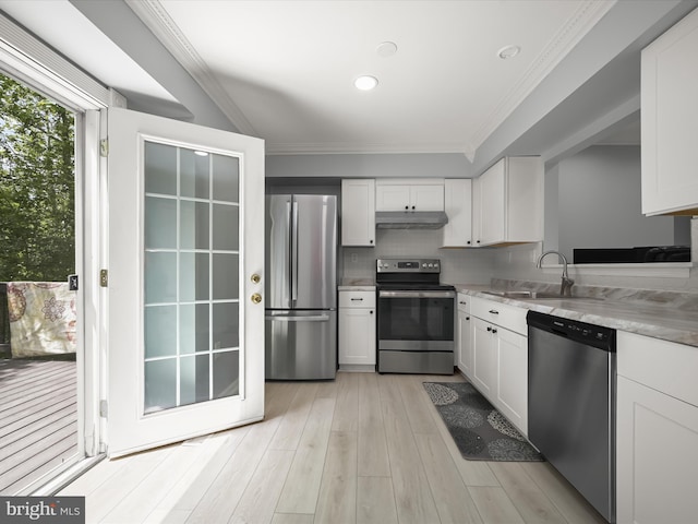 kitchen with stainless steel appliances, under cabinet range hood, a sink, white cabinetry, and ornamental molding