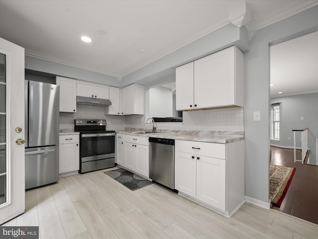kitchen featuring stainless steel appliances, light countertops, under cabinet range hood, crown molding, and backsplash