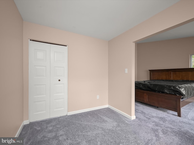 unfurnished bedroom featuring carpet flooring, baseboards, and a closet