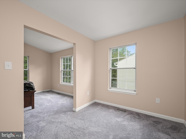 spare room with carpet flooring, baseboards, and vaulted ceiling