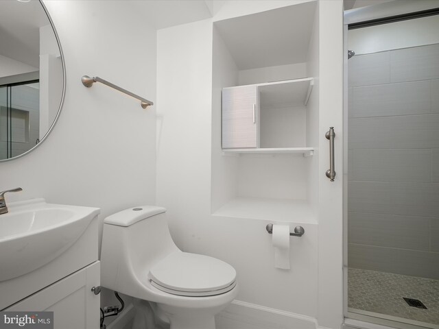 full bathroom featuring a tile shower, toilet, vanity, and baseboards