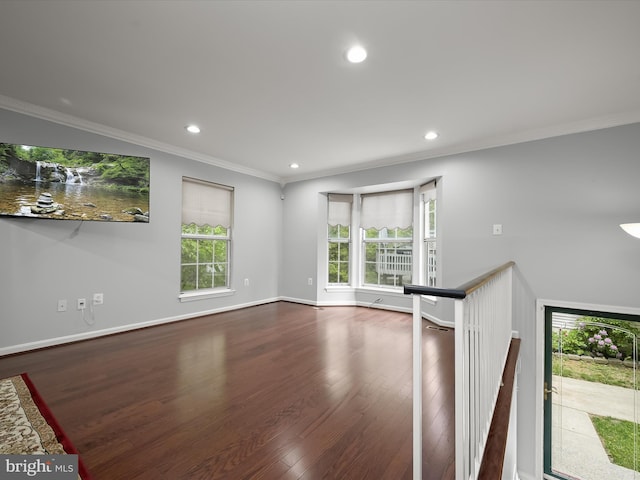 empty room featuring plenty of natural light, wood finished floors, recessed lighting, baseboards, and crown molding