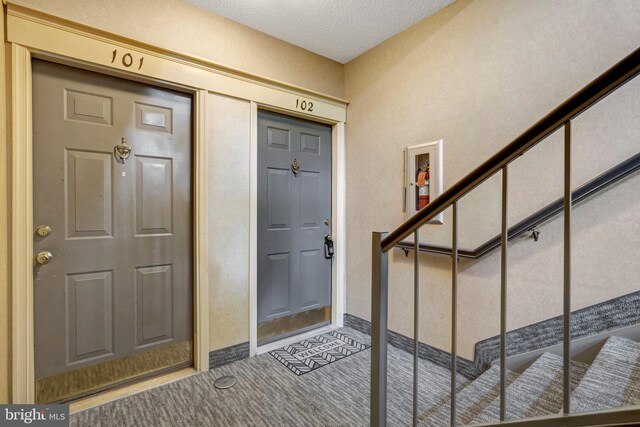 12106 Green Leaf Ct Unit 102, Fairfax, VA 22033 - foyer entrance with carpet floors, stairs, and a textured ceiling
