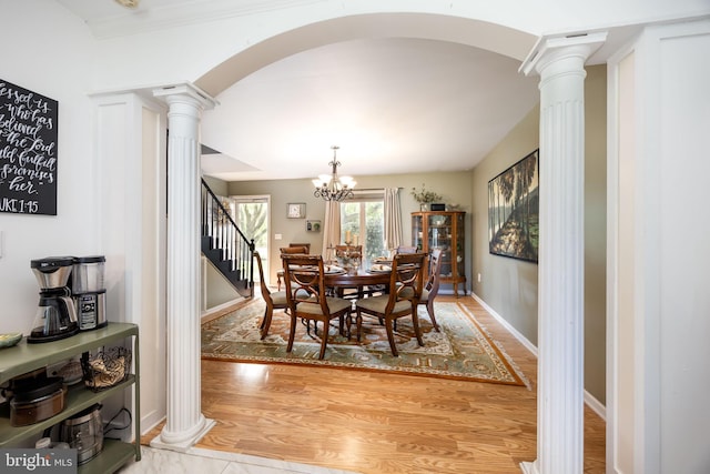 26882 Pratt Rd, Salisbury, MD 21801 - dining space with decorative columns, arched walkways, stairs, a chandelier, and light wood-style floors