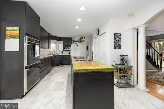 26882 Pratt Rd, Salisbury, MD 21801 - kitchen with decorative columns, a kitchen island, stainless steel cooktop, dark cabinetry, and recessed lighting