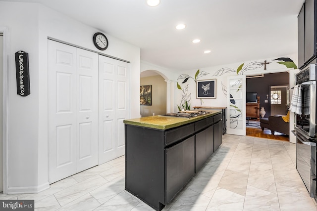 26882 Pratt Rd, Salisbury, MD 21801 - kitchen featuring arched walkways, light marble finish flooring, recessed lighting, a center island, and dark cabinetry