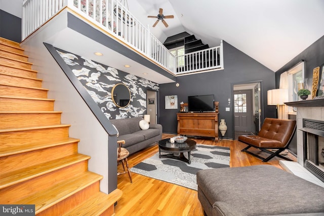26882 Pratt Rd, Salisbury, MD 21801 - living area with high vaulted ceiling, stairs, ceiling fan, a tiled fireplace, and wood finished floors