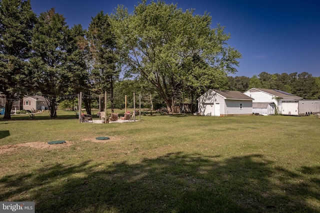 26882 Pratt Rd, Salisbury, MD 21801 - view of green lawn featuring an outbuilding, a detached garage, and view of wooded area
