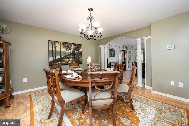 26882 Pratt Rd, Salisbury, MD 21801 - dining area featuring ornate columns, light wood-style flooring, arched walkways, baseboards, and a chandelier