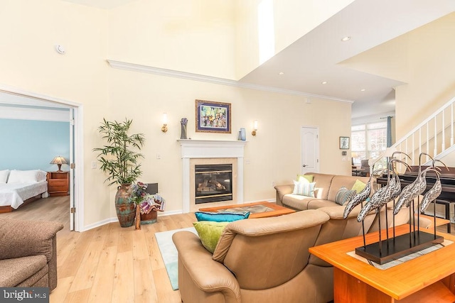 111 Central Parke E, Ocean Pines, MD 21811 - living room with stairway, a glass covered fireplace, light wood-style flooring, baseboards, and ornamental molding