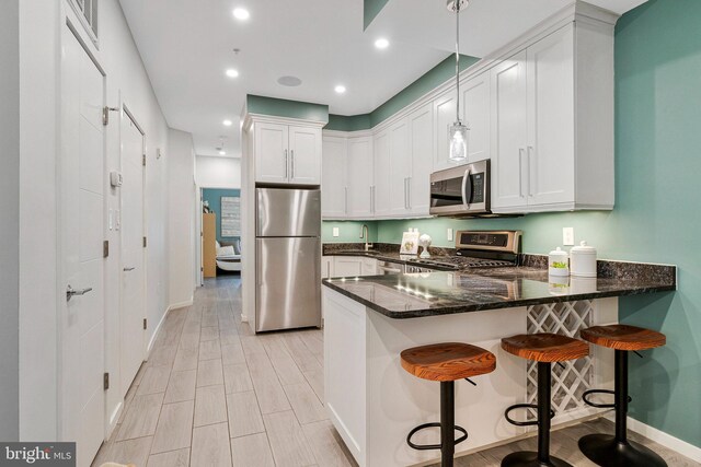 756 Park Rd NW Unit 2, Washington, DC 20010 - kitchen featuring stainless steel appliances, a sink, a peninsula, baseboards, and dark stone counters