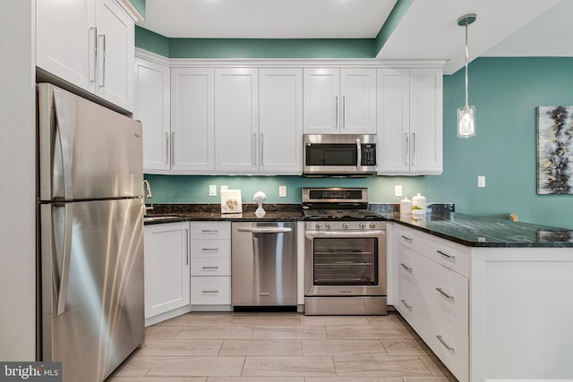kitchen with stainless steel appliances, a peninsula, white cabinets, and decorative light fixtures