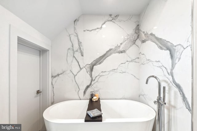 full bath featuring a freestanding tub and vaulted ceiling