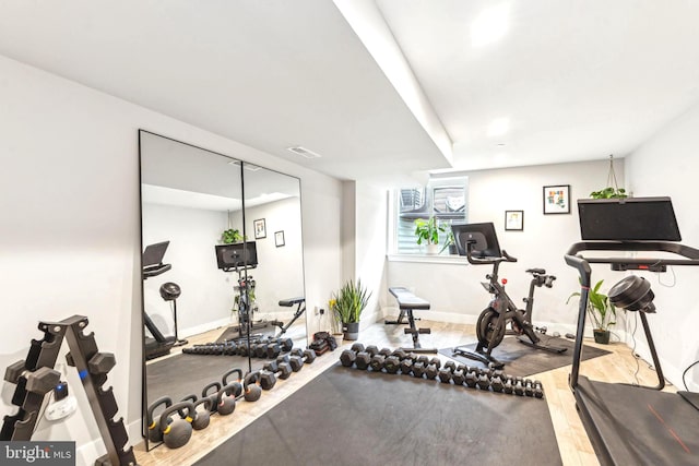 workout area with baseboards and wood finished floors