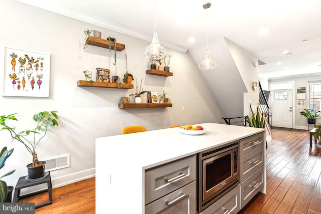 kitchen with stainless steel microwave, open shelves, baseboards, hardwood / wood-style flooring, and light countertops