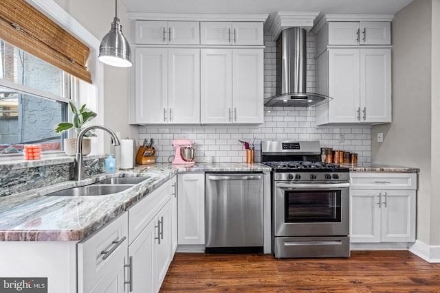 kitchen with appliances with stainless steel finishes, wall chimney exhaust hood, a sink, decorative backsplash, and dark wood finished floors
