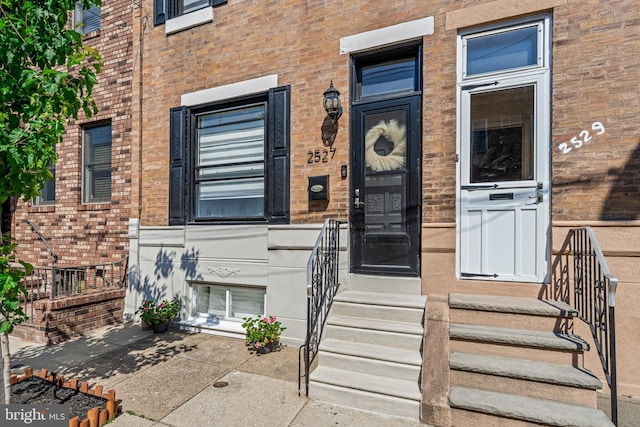 view of exterior entry featuring brick siding