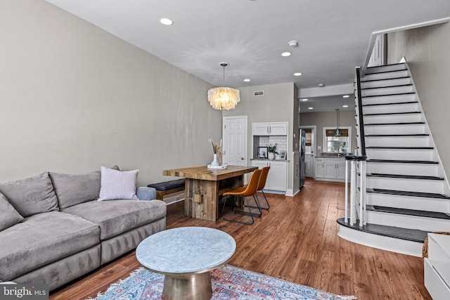 living room featuring a chandelier, stairway, wood finished floors, and recessed lighting