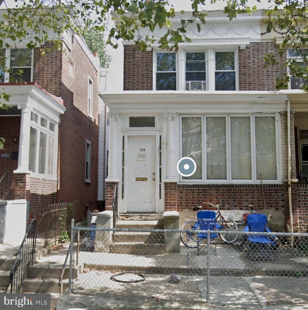 view of front of home with a fenced front yard and brick siding