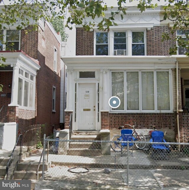 view of front of home with a fenced front yard and brick siding