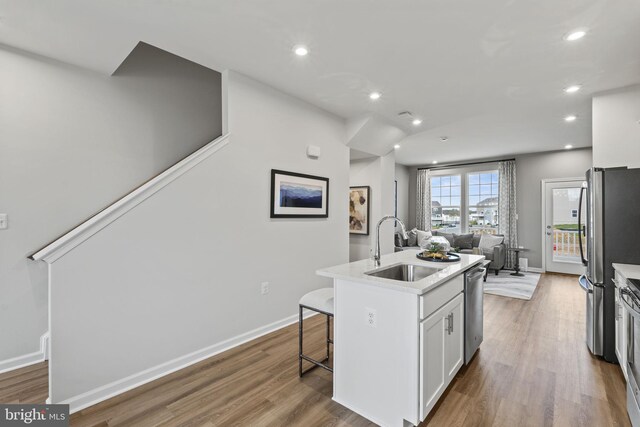 kitchen with a sink, stainless steel appliances, open floor plan, recessed lighting, and white cabinetry