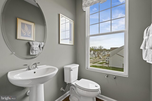 half bath featuring baseboards and toilet
