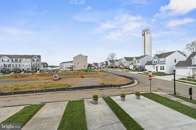 view of asphalt road with traffic signs, a residential view, sidewalks, and curbs