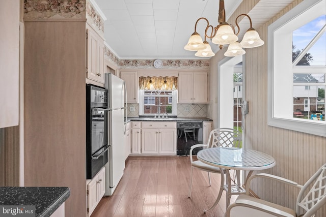 kitchen featuring black appliances, dark countertops, light wood-type flooring, and a warming drawer