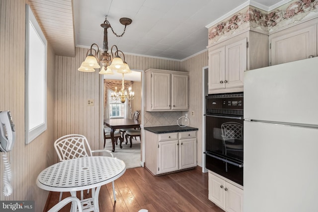 kitchen featuring freestanding refrigerator, black oven, a warming drawer, a chandelier, and ornamental molding