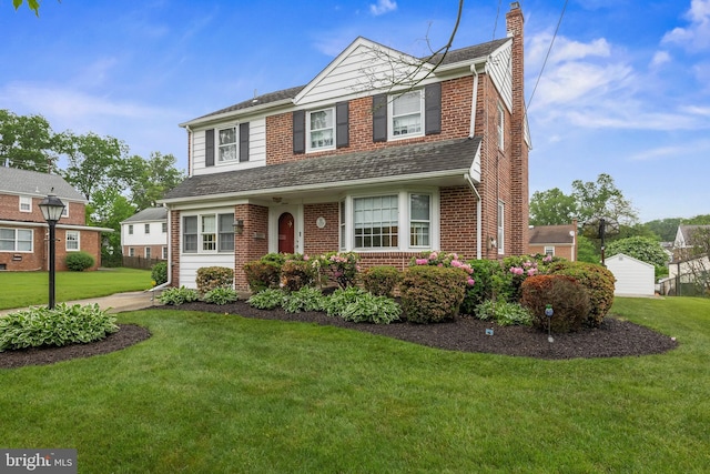 traditional-style house with a chimney, a front lawn, brick siding, and a shingled roof