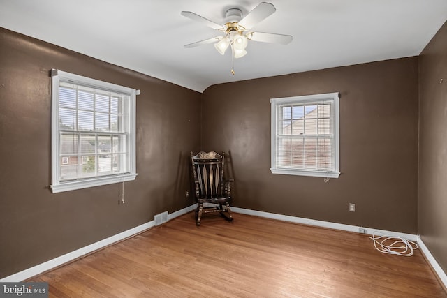 unfurnished room with healthy amount of natural light, light wood finished floors, a ceiling fan, and baseboards