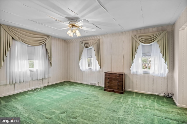 unfurnished room featuring healthy amount of natural light, carpet flooring, a ceiling fan, and wallpapered walls