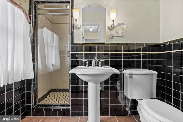 bathroom with a stall shower, toilet, tile walls, and a wainscoted wall