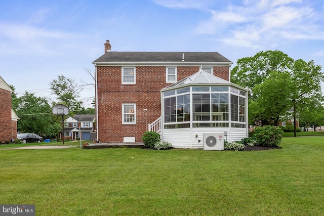 rear view of house with a chimney, a lawn, brick siding, and a cooling unit