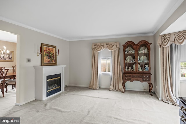 carpeted living room with ornamental molding, a chandelier, a glass covered fireplace, and baseboards