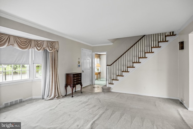foyer featuring stairs, carpet flooring, crown molding, and baseboards