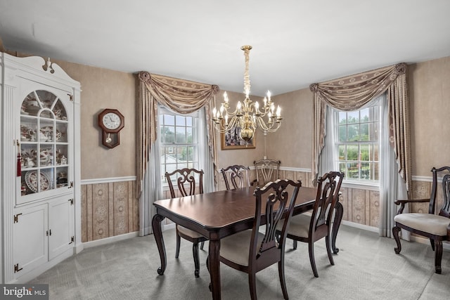 dining room featuring a chandelier, light carpet, baseboards, and a wainscoted wall