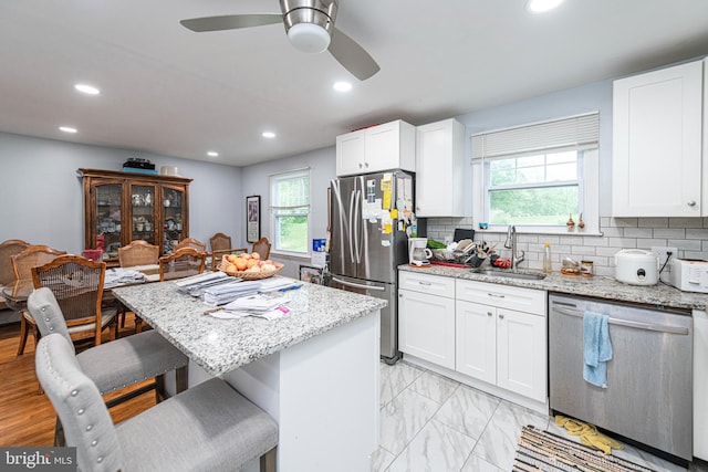 kitchen featuring appliances with stainless steel finishes, a sink, a breakfast bar area, plenty of natural light, and recessed lighting