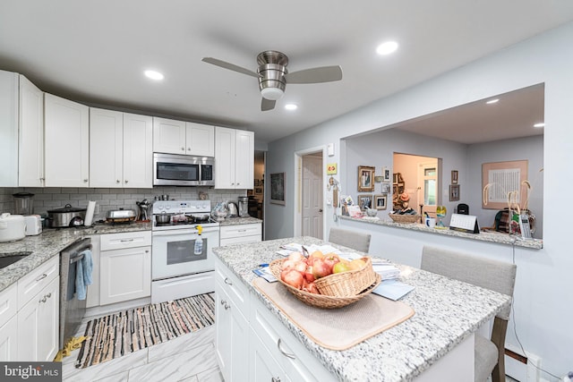 kitchen with stainless steel appliances, decorative backsplash, white cabinetry, recessed lighting, and ceiling fan