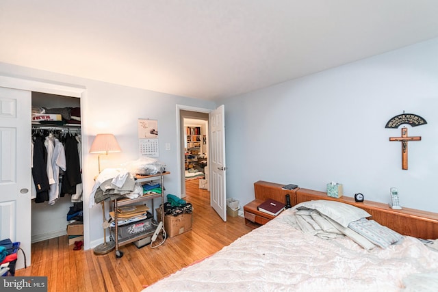 bedroom with a closet, wood finished floors, and baseboards