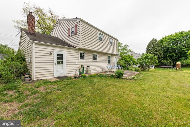 back of house with a yard, a patio, and a chimney