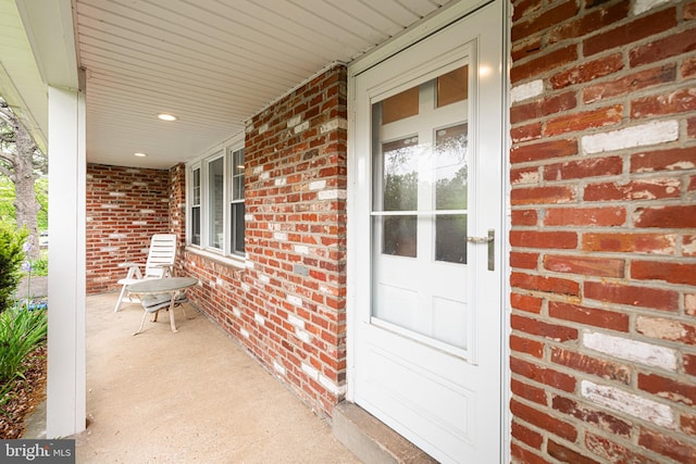 view of exterior entry with covered porch and brick siding