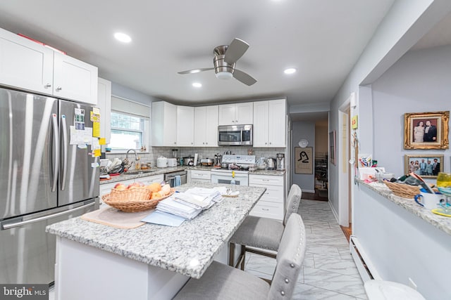 kitchen featuring stainless steel appliances, a sink, a breakfast bar area, light marble finish floors, and recessed lighting