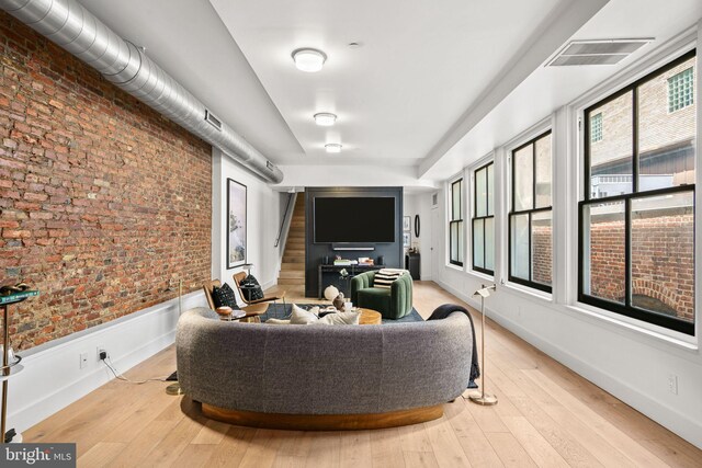 living room featuring brick wall, wood-type flooring, and stairway